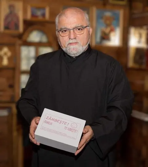 Pr. Ion Doru Iagăru în biserica spitalului din Caracal, cu o cutie din campania „Zâmbește! Familia (noastră) te iubește!”